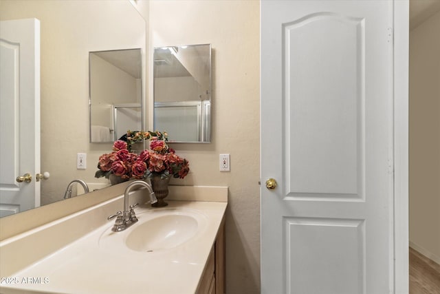 bathroom with hardwood / wood-style flooring, a shower with door, and vanity