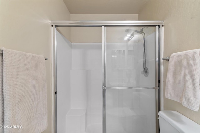 bathroom with toilet and a shower with shower door