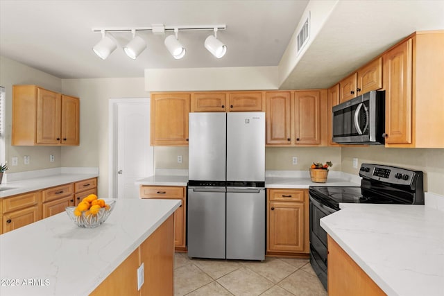 kitchen featuring stainless steel appliances, light tile patterned flooring, and light stone countertops