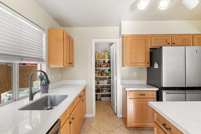 kitchen with light stone countertops, sink, stainless steel fridge, light tile patterned flooring, and light brown cabinets