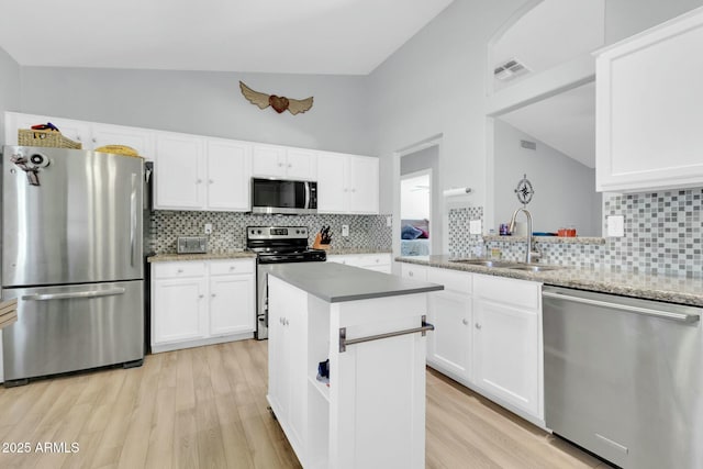 kitchen featuring visible vents, a sink, light wood finished floors, stainless steel appliances, and decorative backsplash