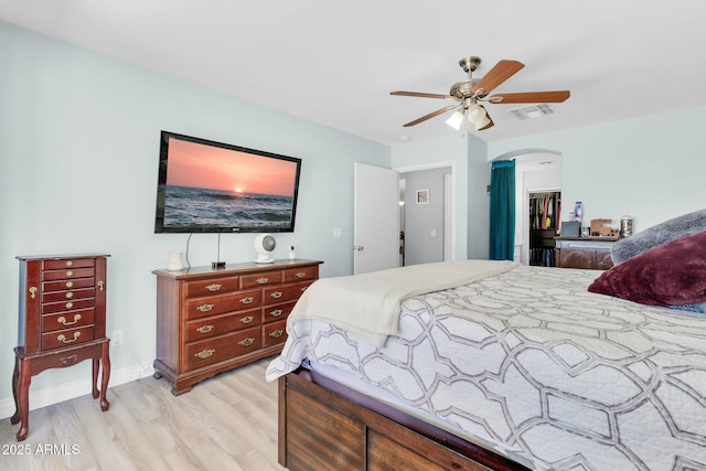 bedroom featuring light wood-style floors, ceiling fan, arched walkways, a closet, and visible vents