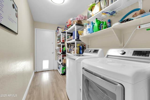 laundry room featuring washing machine and clothes dryer, light wood-type flooring, laundry area, and baseboards