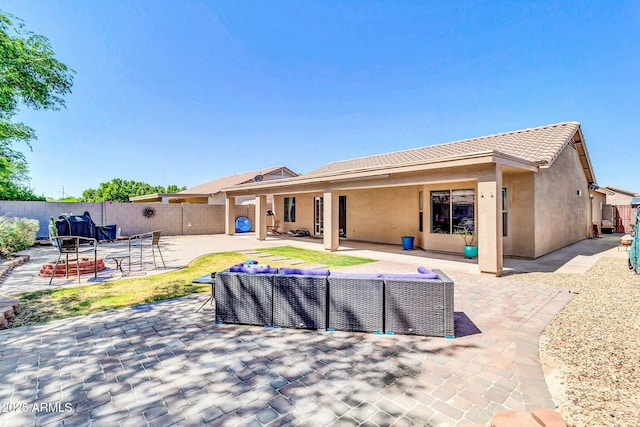 rear view of property featuring outdoor lounge area, a fenced backyard, a tile roof, a patio, and stucco siding