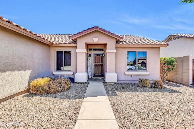property entrance featuring a tile roof and stucco siding