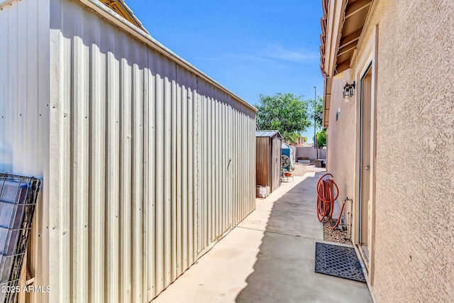 view of side of home featuring a patio area, stucco siding, and an outbuilding