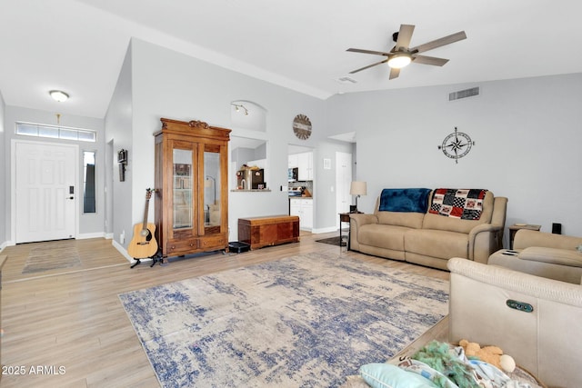 living area featuring visible vents, baseboards, light wood-type flooring, a ceiling fan, and vaulted ceiling