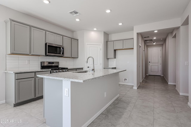 19115 N Los Gabrieles Way, Maricopa, AZ 85138 - kitchen with a sink, stainless steel appliances, gray cabinets, an island with sink, and decorative backsplash