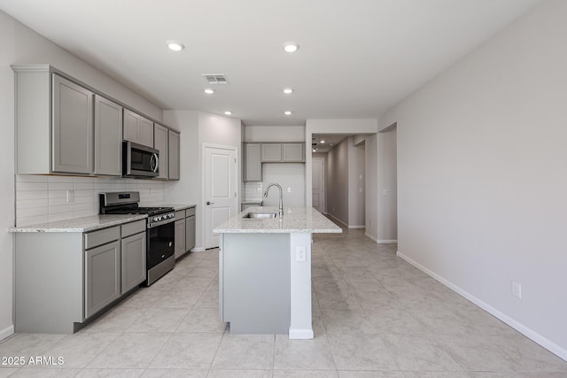 19115 N Los Gabrieles Way, Maricopa, AZ 85138 - kitchen featuring stainless steel appliances, a sink, gray cabinets, decorative backsplash, and light stone counters