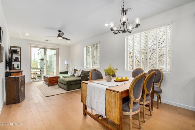 dining room featuring ceiling fan with notable chandelier and light hardwood / wood-style flooring