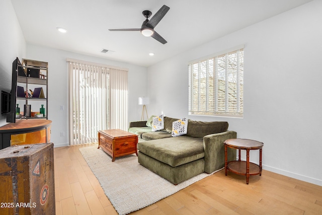 living room with ceiling fan, wood-type flooring, and plenty of natural light