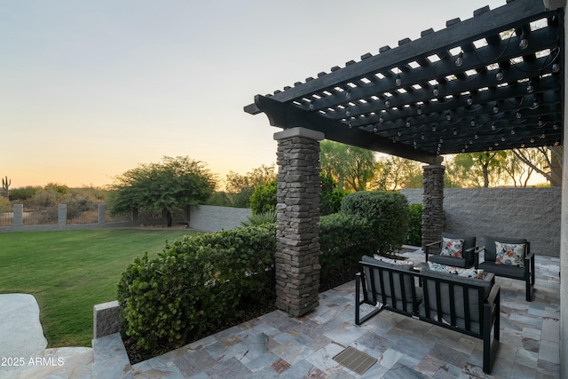 patio terrace at dusk featuring a pergola and a lawn