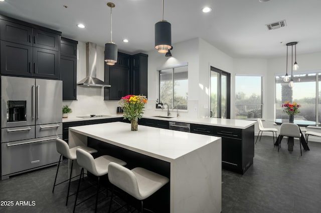 kitchen with wall chimney exhaust hood, a center island, hanging light fixtures, and appliances with stainless steel finishes