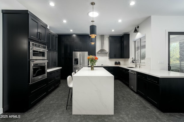 kitchen featuring sink, decorative light fixtures, a center island, wall chimney range hood, and appliances with stainless steel finishes