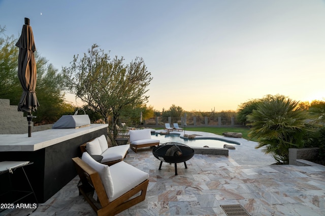 patio terrace at dusk featuring a bar and an outdoor fire pit