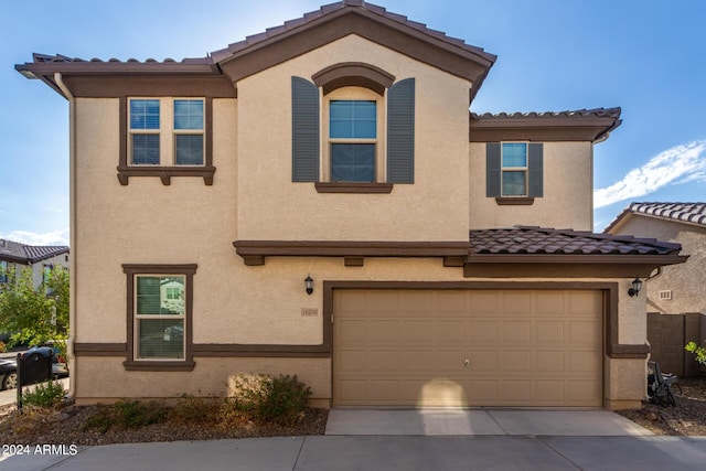 view of front of home with driveway, an attached garage, a tile roof, and stucco siding