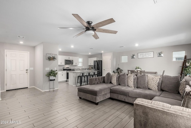 living area featuring light wood-style flooring, baseboards, a ceiling fan, and recessed lighting