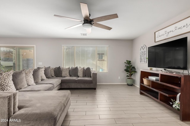 living room with a healthy amount of sunlight, ceiling fan, visible vents, and baseboards