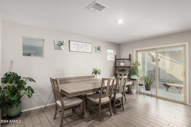 dining area with light wood-type flooring, visible vents, and baseboards