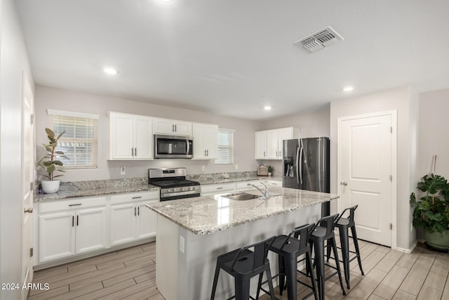 kitchen featuring appliances with stainless steel finishes, a sink, visible vents, and wood tiled floor