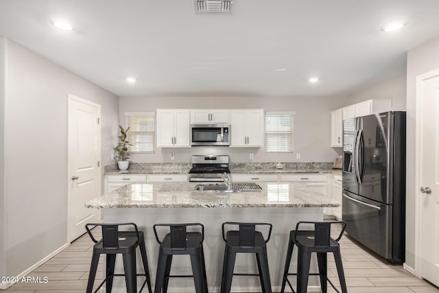 kitchen featuring stainless steel appliances, a breakfast bar area, a sink, and visible vents