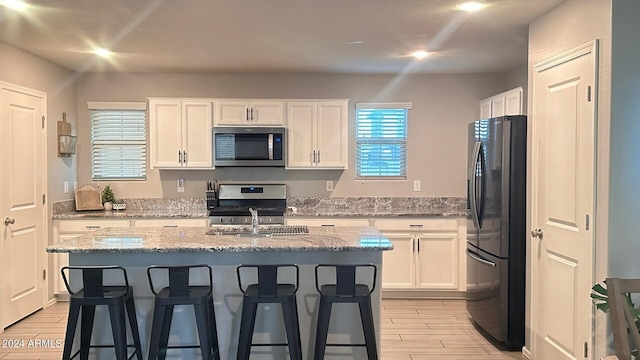 kitchen with range, white cabinetry, light hardwood / wood-style flooring, and black refrigerator with ice dispenser