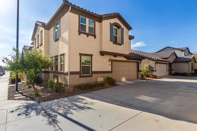 mediterranean / spanish-style home with a garage, a tile roof, concrete driveway, and stucco siding