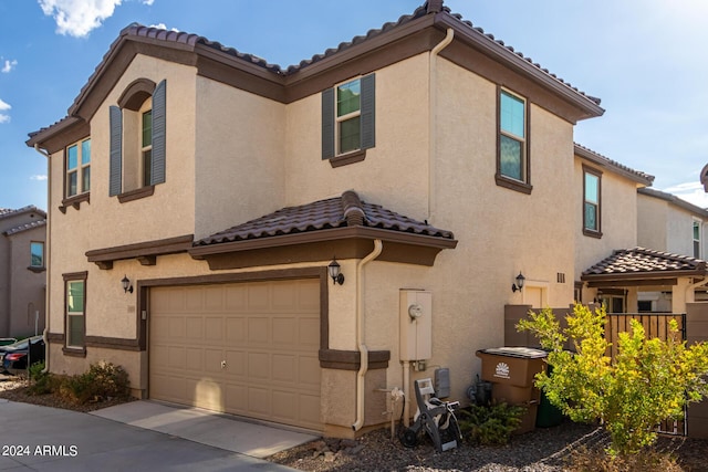 mediterranean / spanish-style house with a tiled roof, an attached garage, and stucco siding