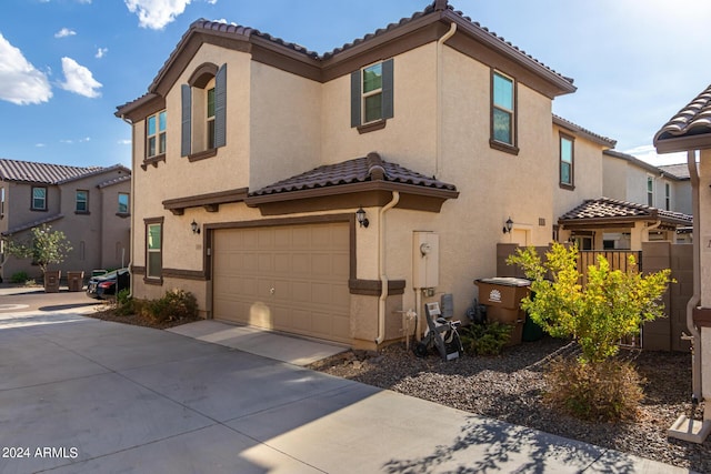 mediterranean / spanish-style house with a garage, a tiled roof, concrete driveway, and stucco siding