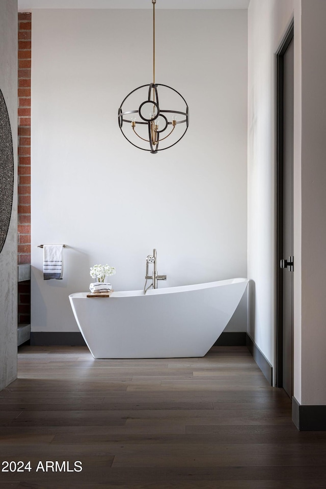 bathroom featuring wood-type flooring, an inviting chandelier, and a bathtub