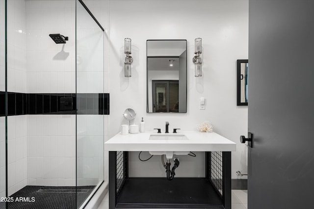 bathroom with a shower with door and sink