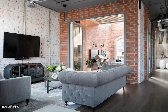 living room with hardwood / wood-style flooring and brick wall