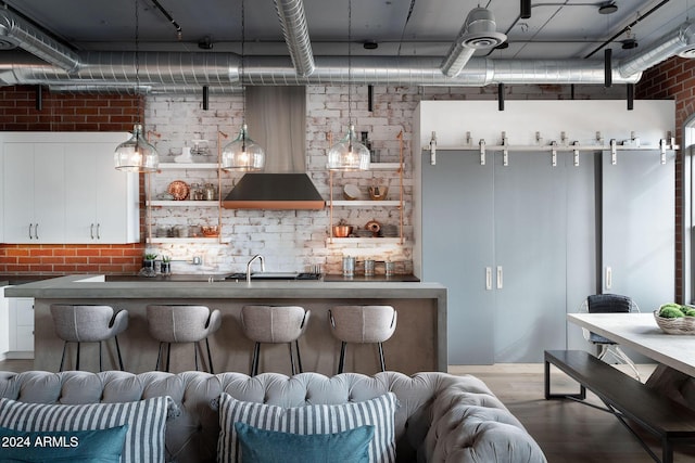 bar with sink, hardwood / wood-style flooring, white cabinetry, and brick wall