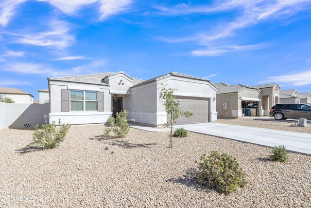 view of front of property featuring driveway, an attached garage, fence, and stucco siding