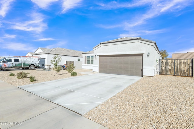 ranch-style house featuring stucco siding, concrete driveway, an attached garage, fence, and an outdoor structure