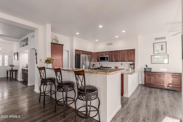 kitchen featuring light stone countertops, appliances with stainless steel finishes, a breakfast bar, and kitchen peninsula