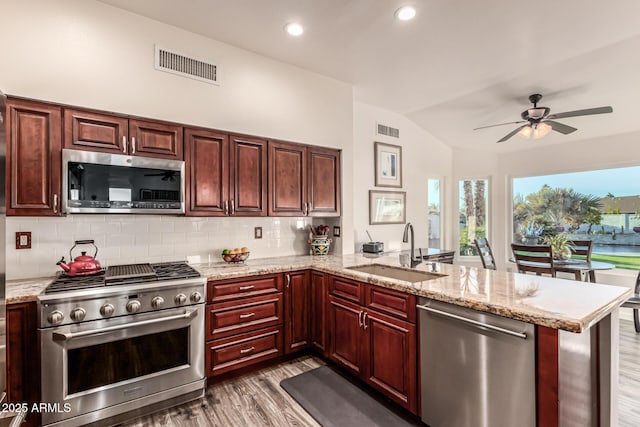 kitchen featuring stainless steel appliances, dark hardwood / wood-style flooring, kitchen peninsula, and sink