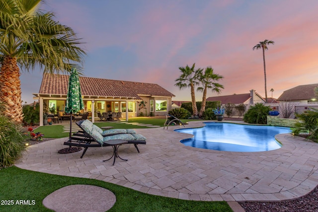 pool at dusk with a yard and a patio area