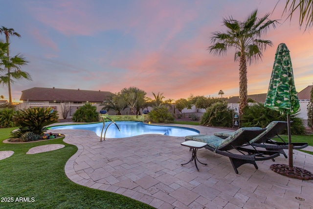 pool at dusk with a lawn and a patio