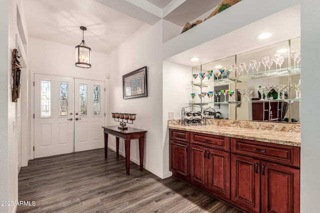 bar featuring pendant lighting, light stone countertops, and dark wood-type flooring