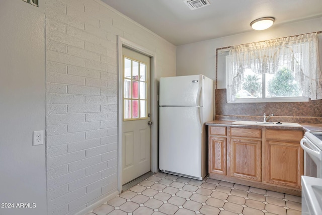 kitchen featuring brick wall, white appliances, and sink