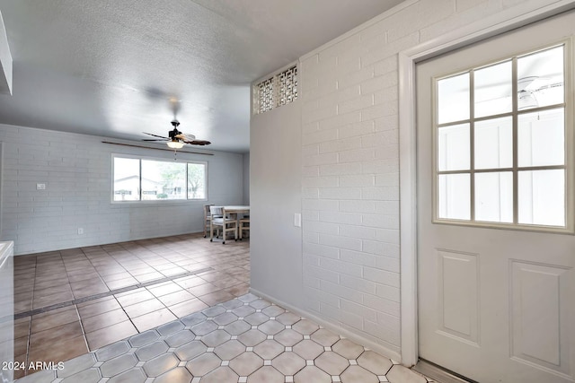 interior space with ceiling fan, brick wall, and a textured ceiling