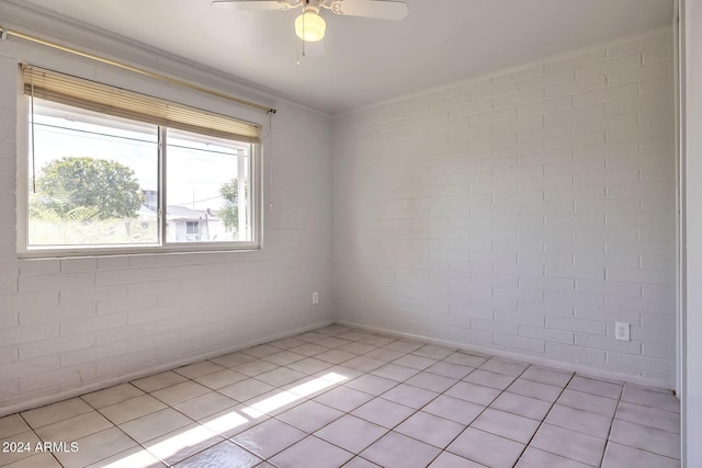 unfurnished room with ceiling fan, light tile patterned flooring, and brick wall