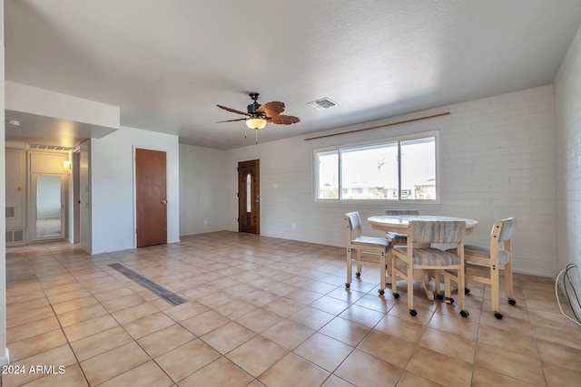 dining room with light tile patterned floors, ceiling fan, and brick wall