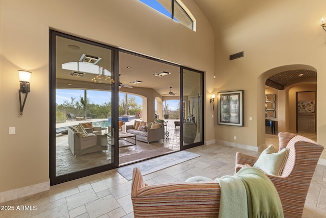 living room featuring stone tile floors, arched walkways, baseboards, and visible vents