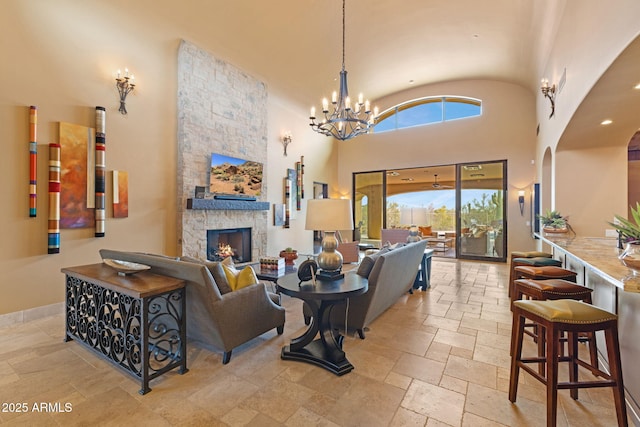 living room featuring arched walkways, high vaulted ceiling, a stone fireplace, and stone tile floors