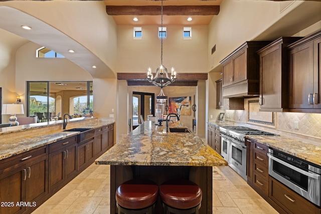 kitchen with a sink, a towering ceiling, stone tile floors, and range with two ovens