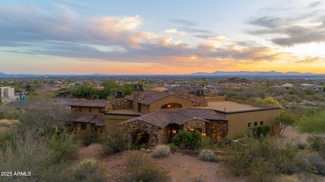 mediterranean / spanish house featuring a mountain view, stucco siding, a tiled roof, and a chimney
