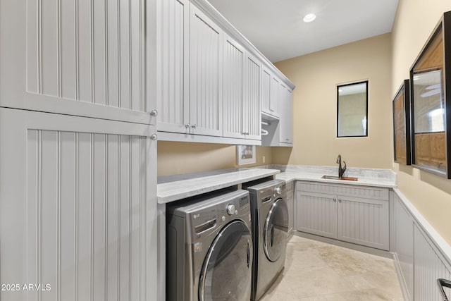 laundry room with a sink, washer and clothes dryer, cabinet space, and wainscoting