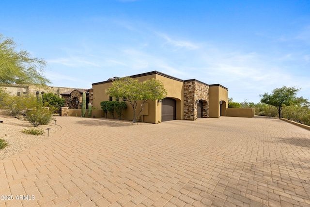 view of front of house featuring curved driveway, an attached garage, and stucco siding
